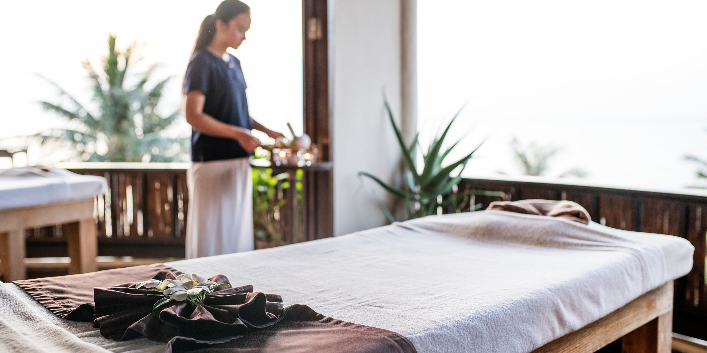 Massage therapist at a spa and a bed with some decoration.