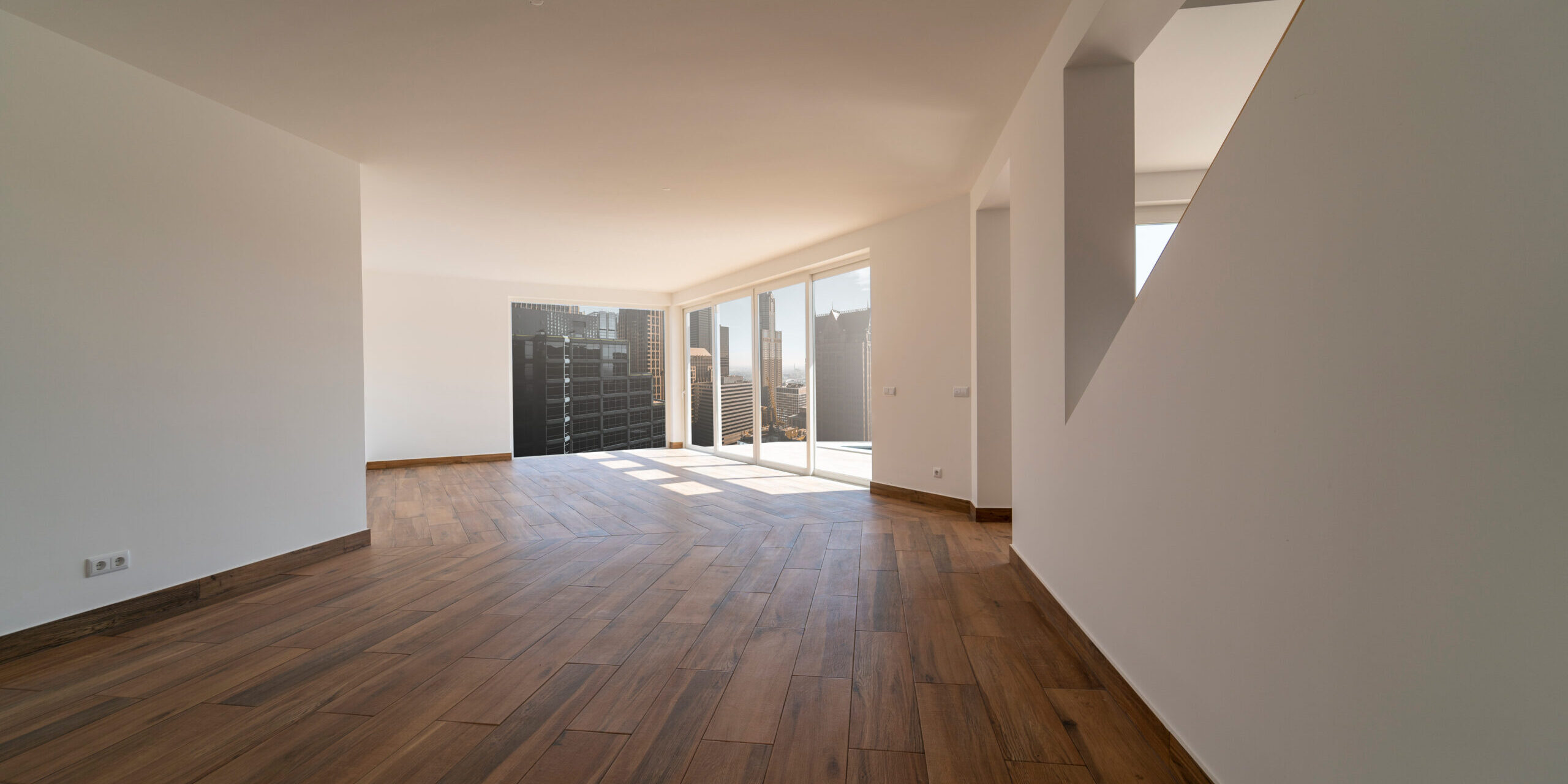 Empty room with dark wooden floating laminate flooring.