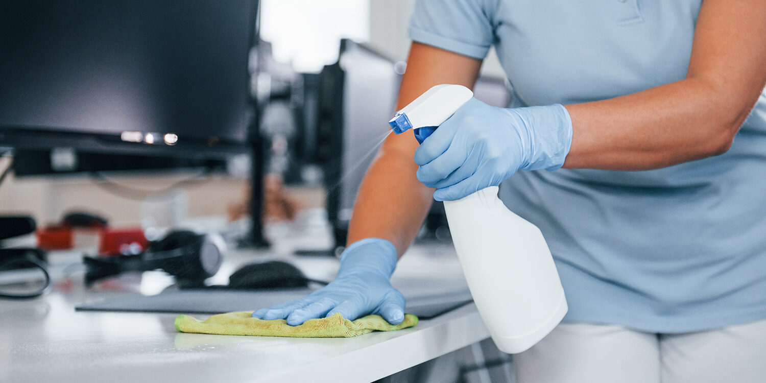 Close up view of woman in protective gloves that cleaning tables in the office.